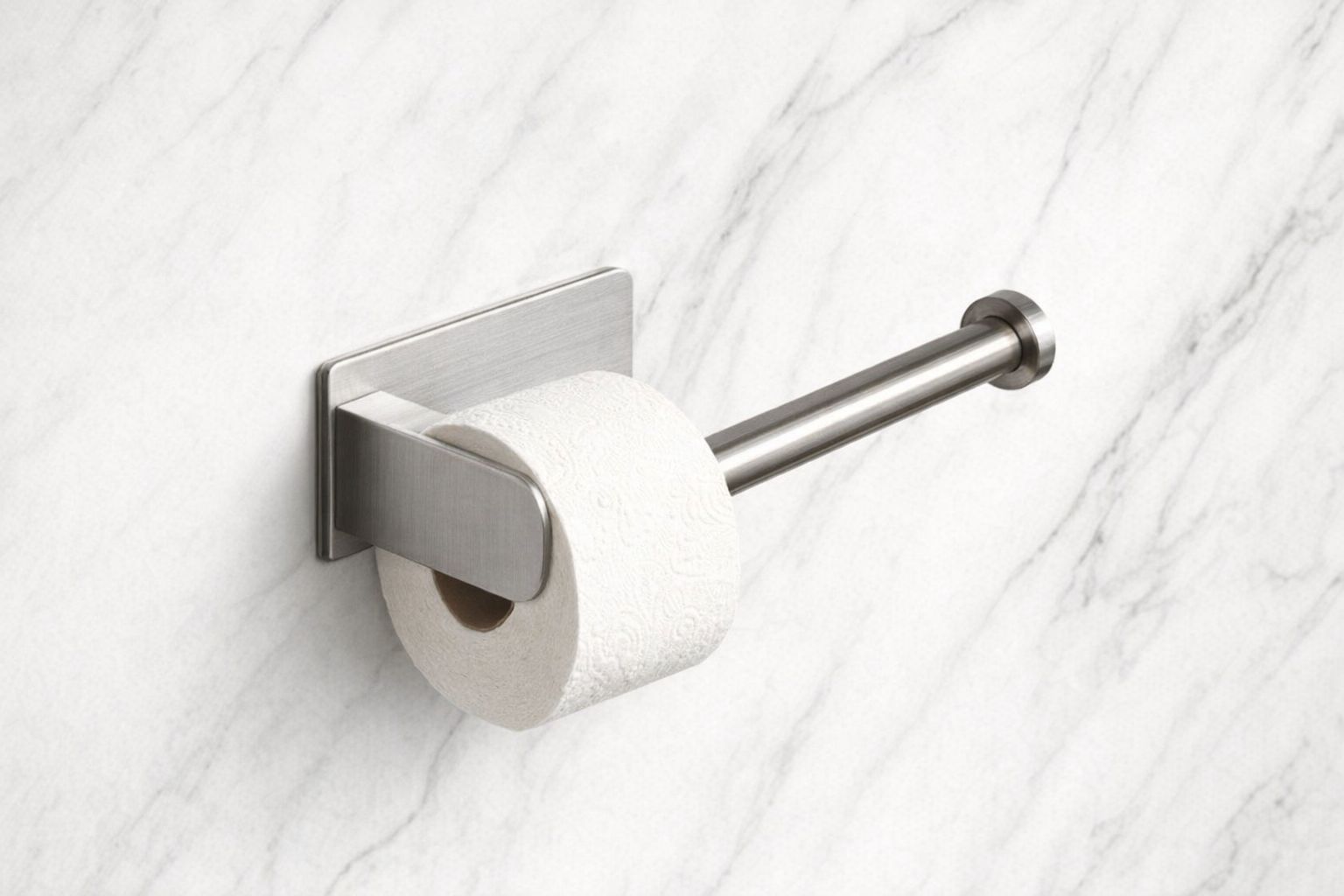 Porte-papier toilette en acier brossé adhésif fixé sur un mur en marbre.